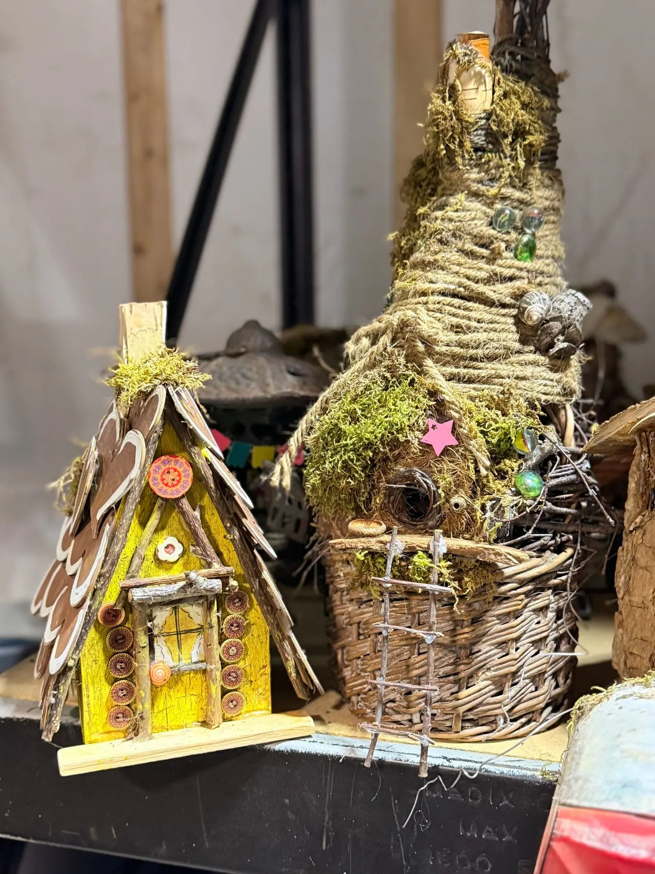 A detailed faerie house with a moss roof and a warm yellow interior.