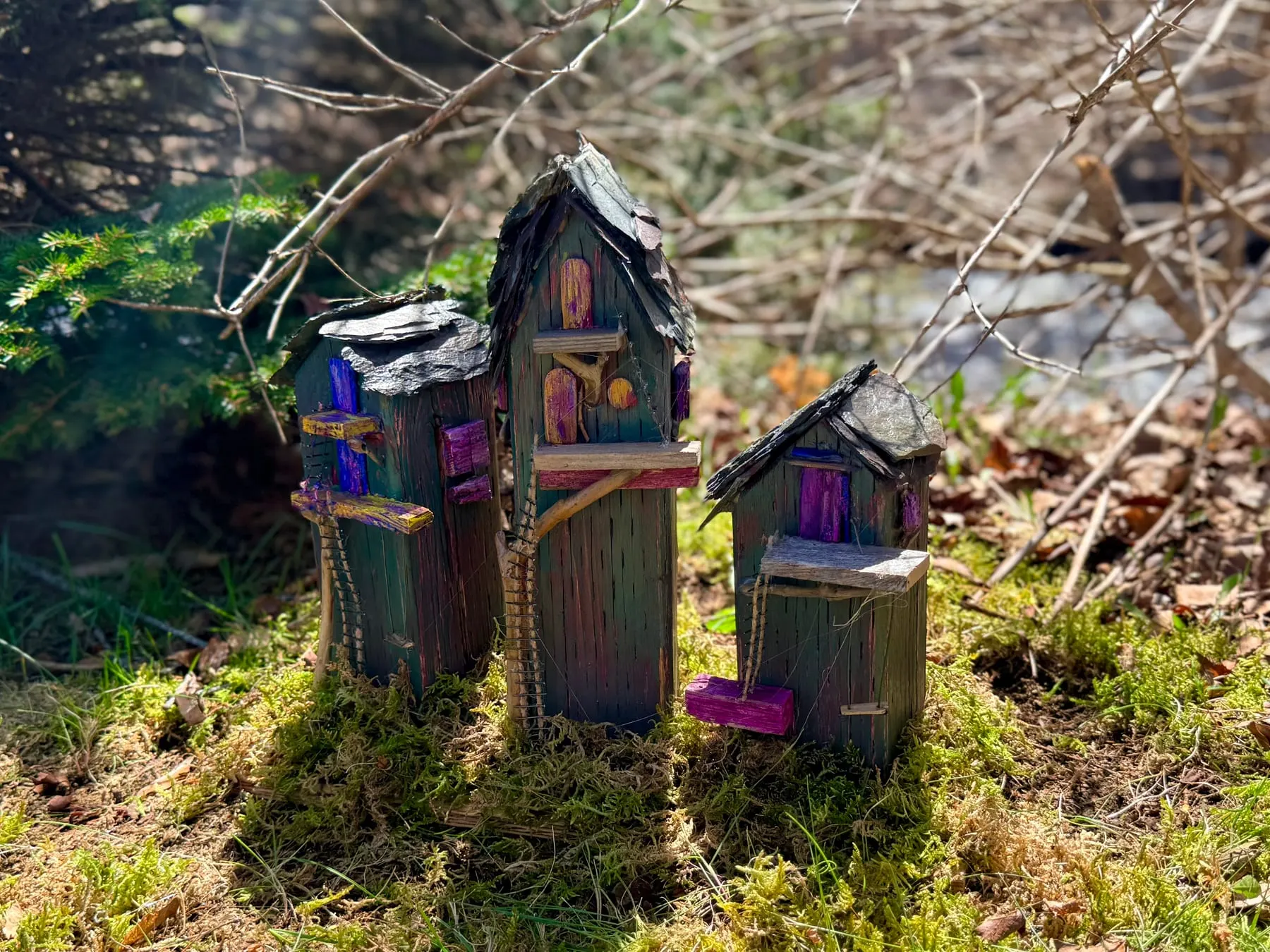 A little cluster of tiny faerie houses nestled together in a mossy patch of the woods.