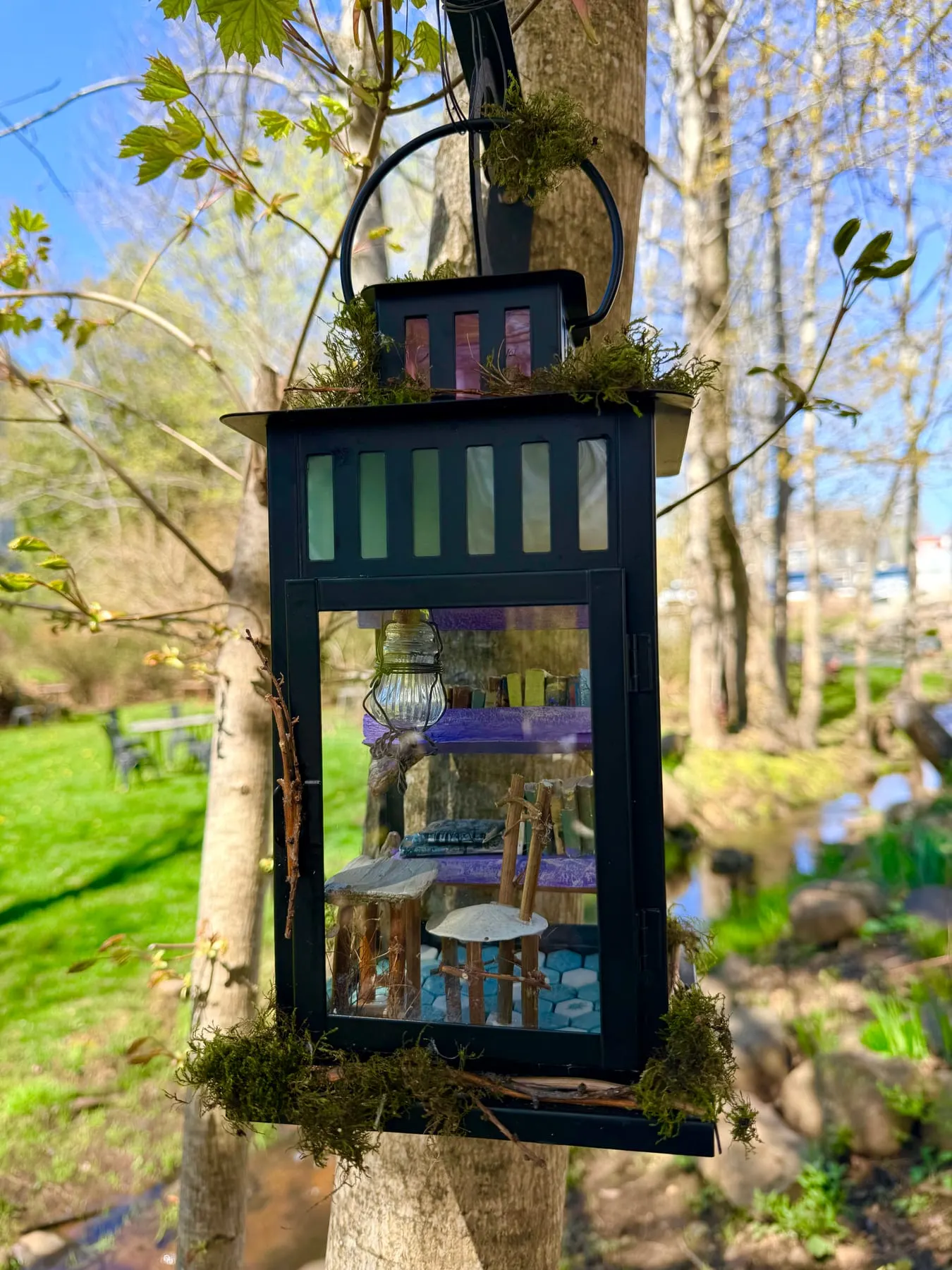 A tall lantern-style faerie house glowing beside the river on the Maggie Maggie River Trail.
