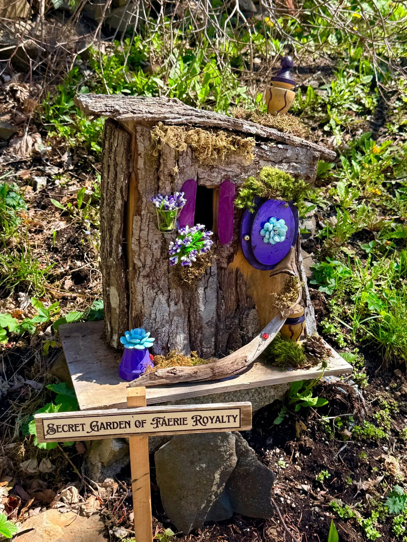 A hand-lettered Secret Garden trail sign beside a purple faerie door.