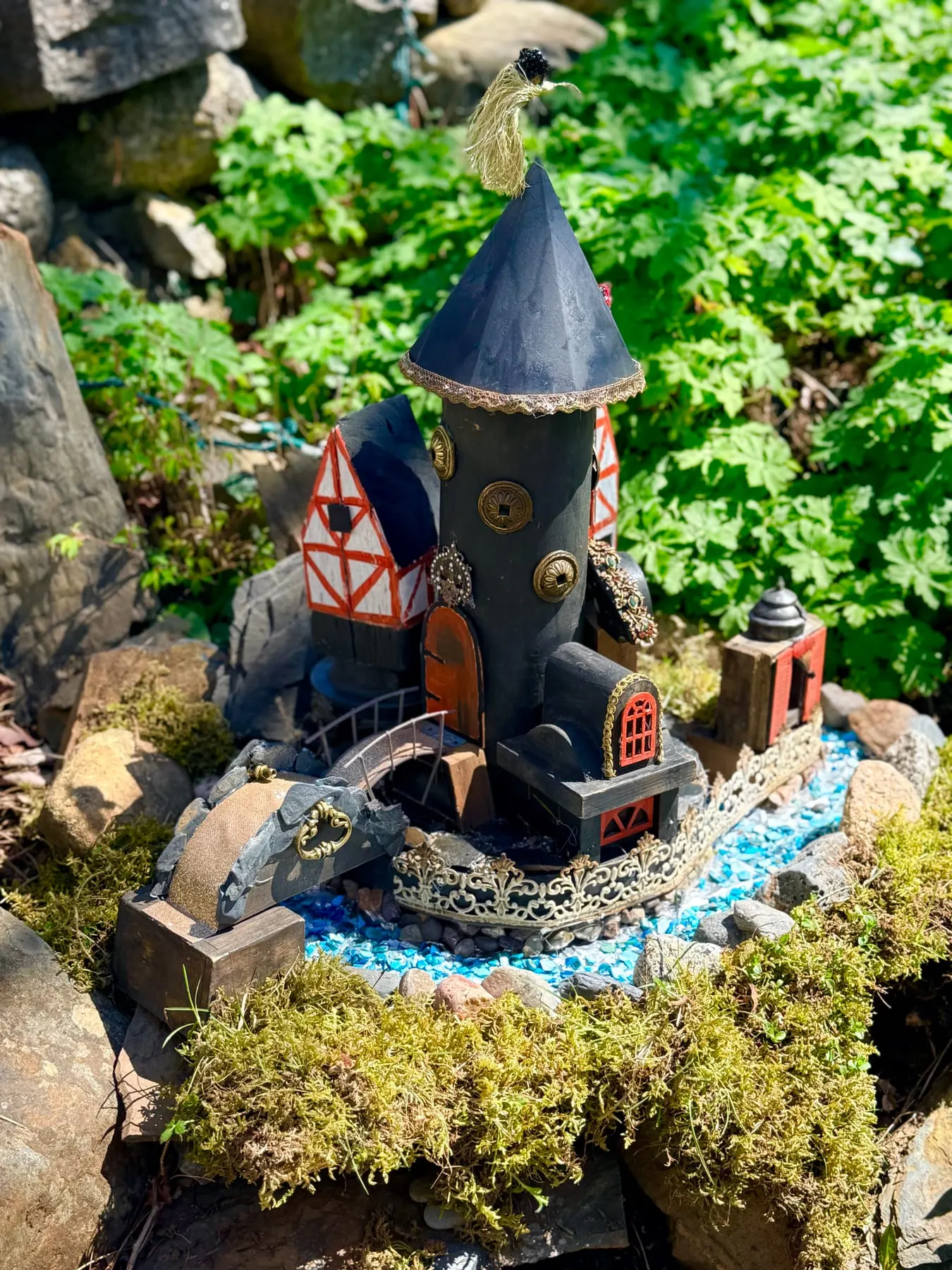 A dramatic dark faerie castle with a little bridge over a moss moat.