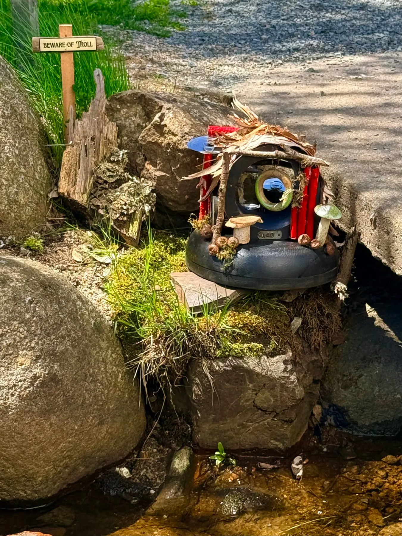 A weathered faerie house sheltering among grey boulders after rough weather.