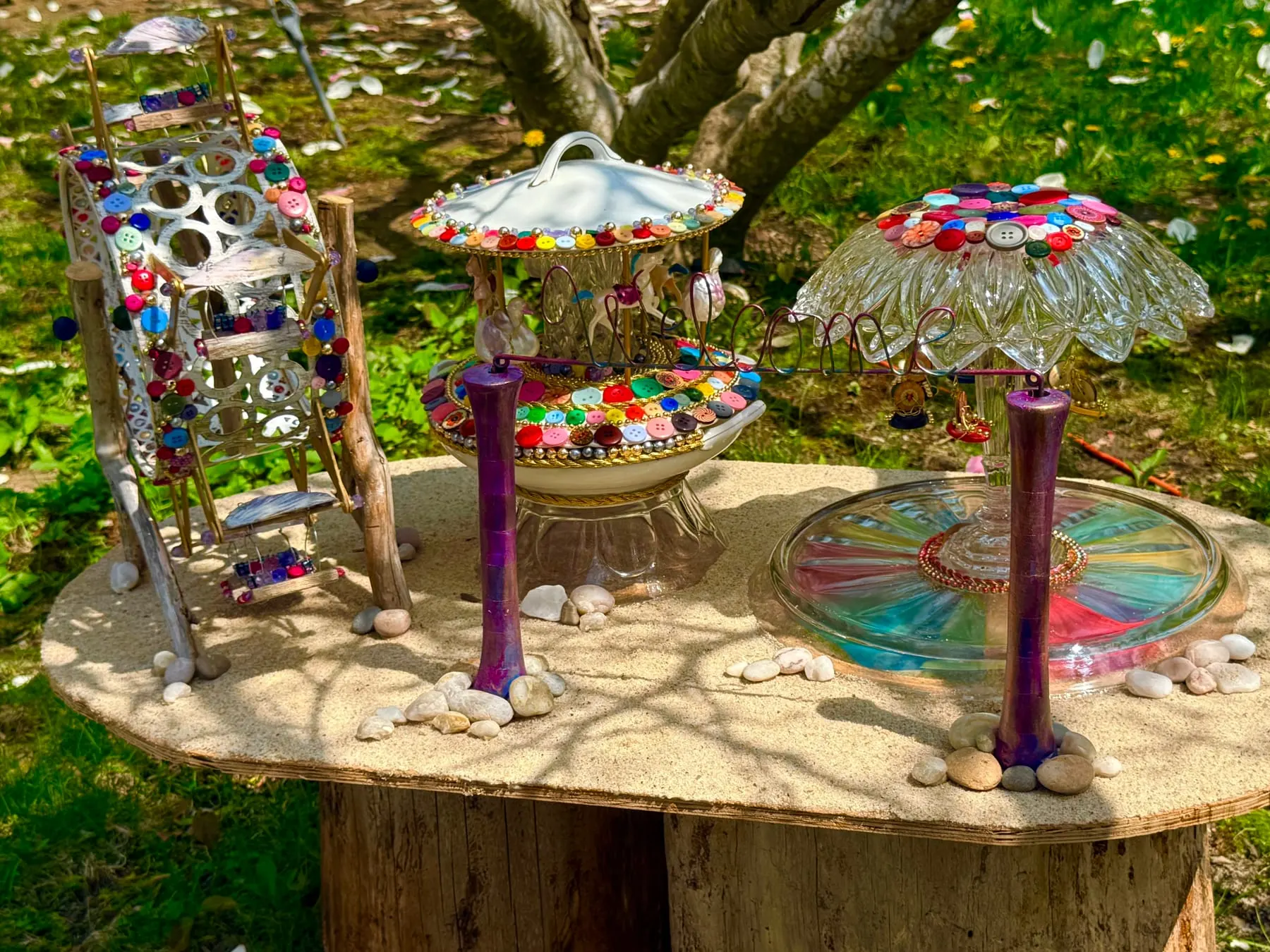 A twinkling faerie carousel of beads and buttons set out on a tree stump.