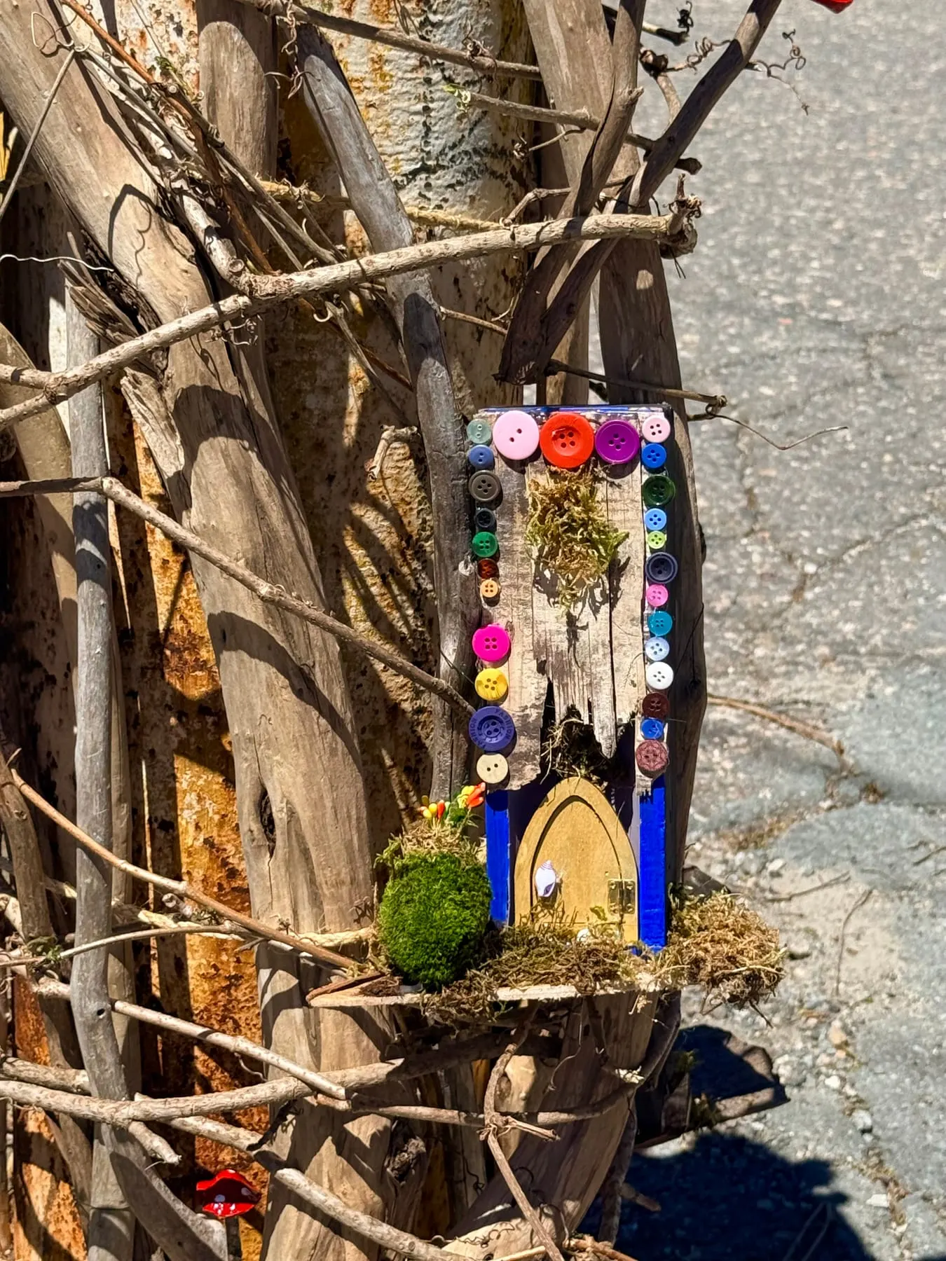 A faerie door in a tree trunk hung with tiny beaded decorations.