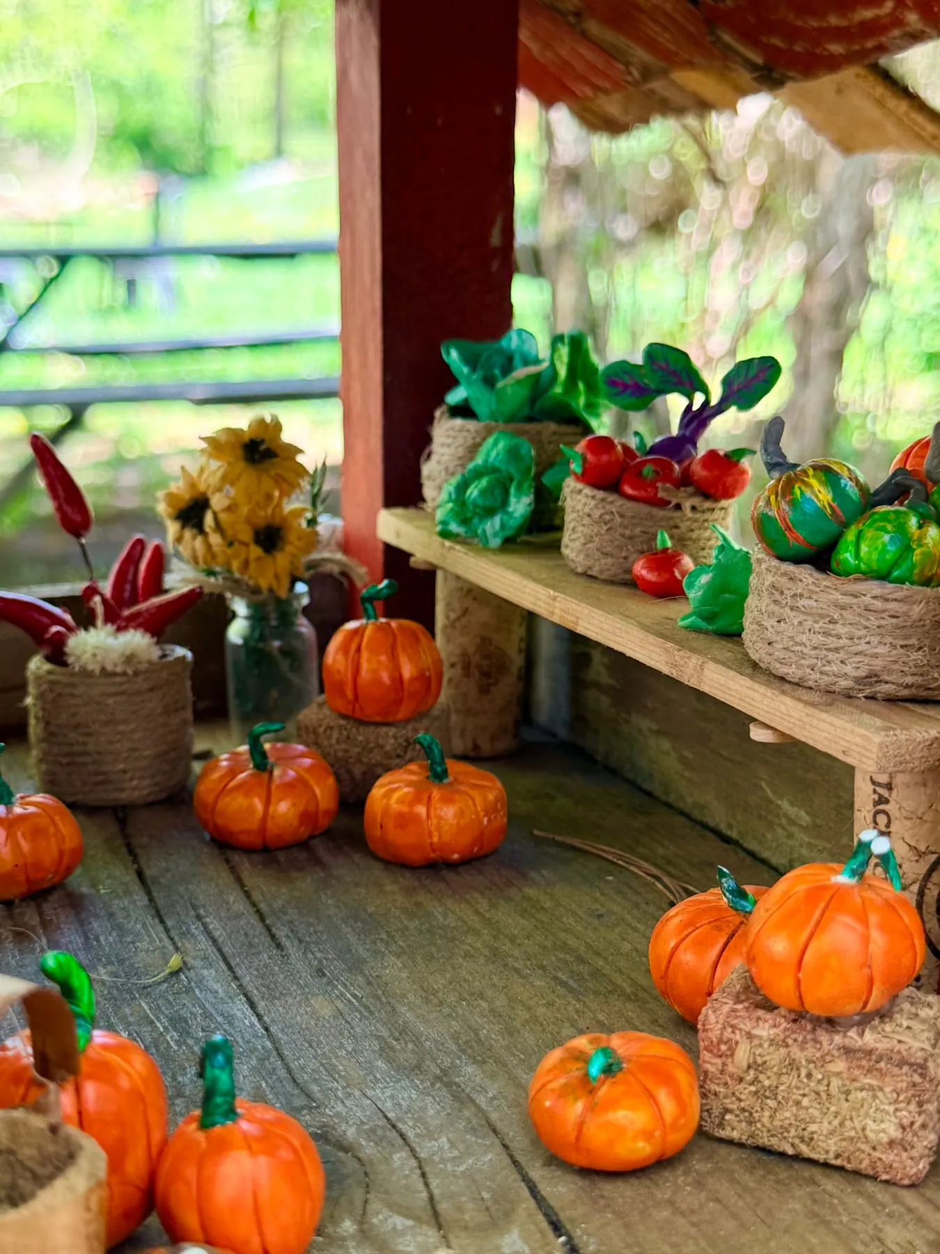 A tiny faerie farm market stall laden with clay pumpkins, sunflowers and vegetables.